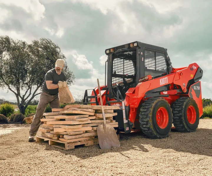 Operator working beside a compact loader